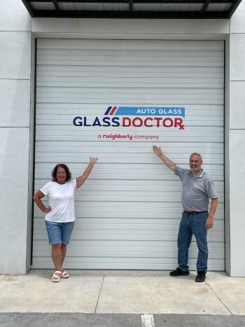 Glass Doctor Auto of Cedar Park owners Russ and Susan Burleson point to the Glass Doctor logo on their building.