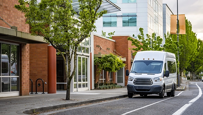 A picture of a white fleet van driving down the street.