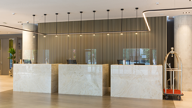 A picture of a sneeze guard installed at a hotel front desk.