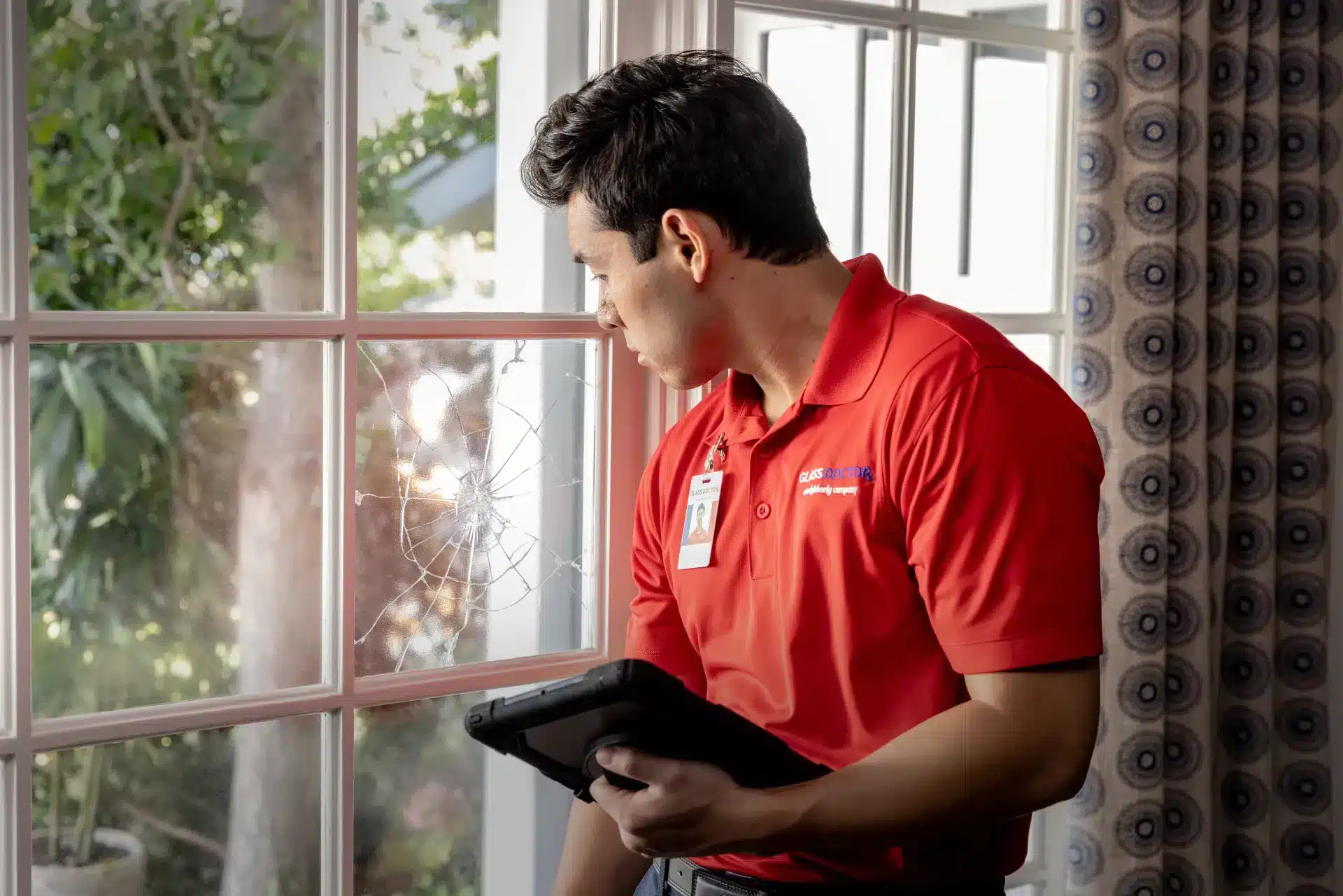 A Glass Doctor technician cleaning a home window pane after home glass repair and replacement.