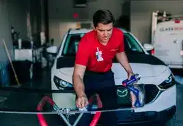 Auto glass technician cleaning and preparing a car windshield for windshield repair and replacement.
