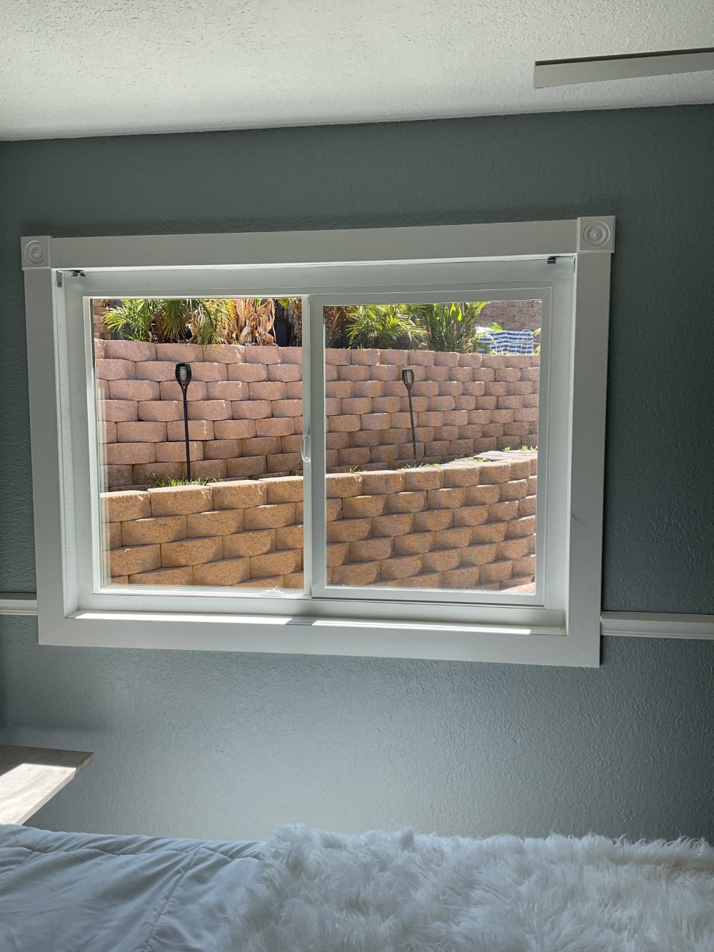 Retrofit sliding window installation in a Canyon Lake, CA bedroom with white frame and trim, improving energy efficiency and modernizing the home interior.