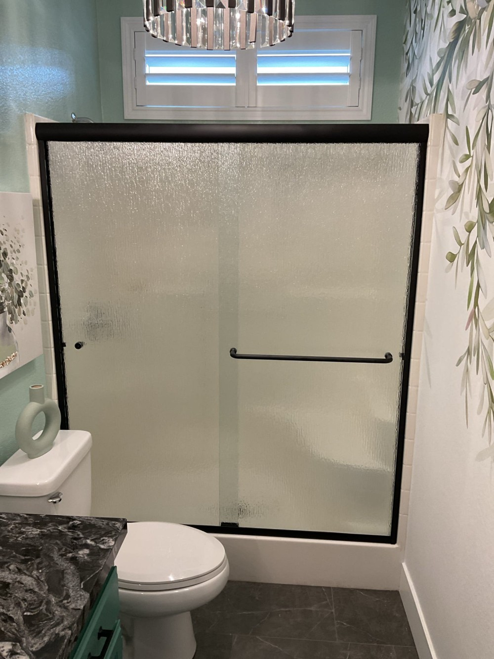 Sliding bypass shower enclosure with matte black frame and rain glass panels, installed in a Murrieta, CA bathroom for added privacy and contemporary style.