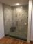 Custom glass shower door with granite walls and a bench
