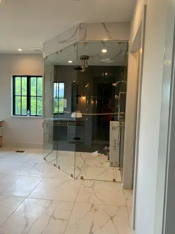 A large corner shower enclosure with two sides of frameless glass and an angled frameless glass door by Glass Doctor of Nashville.