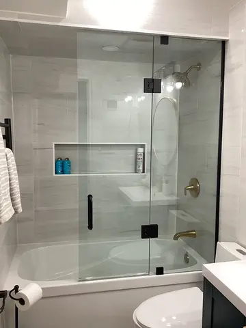 A frameless glass shower door with black hardware on a bathtub by Glass Doctor of Barrie, ON.