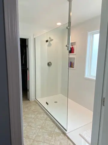 A white tile shower with frameless glass splash panel by Glass Doctor of Raleigh