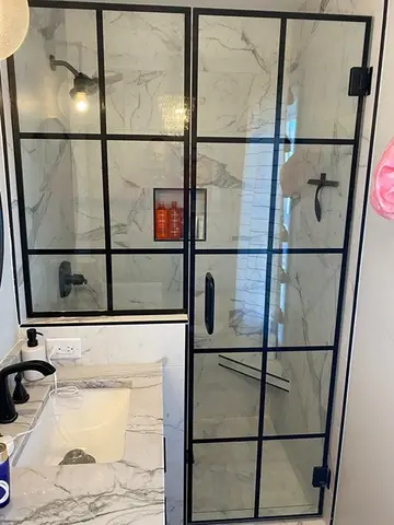 Two black-framed glass panels installed on a white marble shower enclosure by Glass Doctor of Nashville.