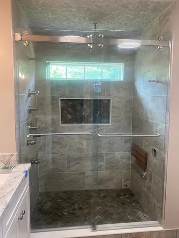 A tiled shower with frameless glass sliding doors and brushed nickel hardware by Glass Doctor of Raleigh