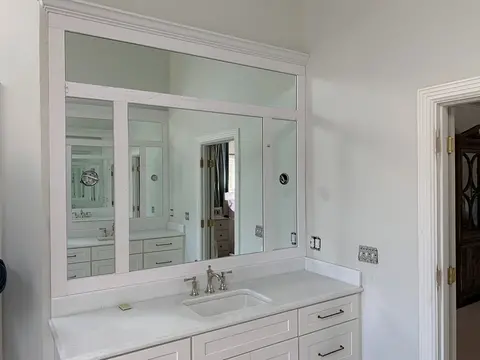 A decorative bathroom mirror with four panels in a white wood frame over a white countertop by Glass Doctor of Nashville.
