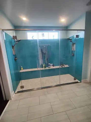 A double shower with blue walls and clear glass shower doors with a metal top frame and two swinging doors by Glass Doctor Home + Business of Myrtle Beach.