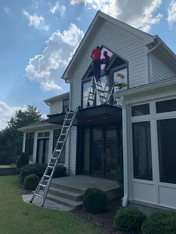 A Glass Doctor of Nashville service professional installing a feature window above the entry way of a house.
