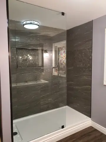 A frameless fixed glass 2/3 panel on a dark grey tile shower installed by Glass Doctor of Barrie, ON.