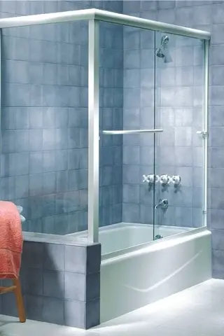 A framed shower enclosure with a sliding door and gray hardware installed on a tub with blue tiles.