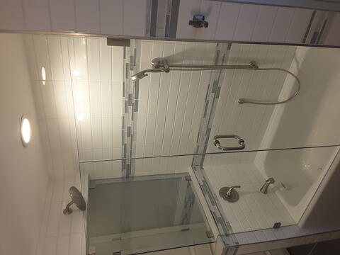 A second angle of a tub with white and gray tiles and frameless glass shower doors installed by Glass Doctor of Sarasota.