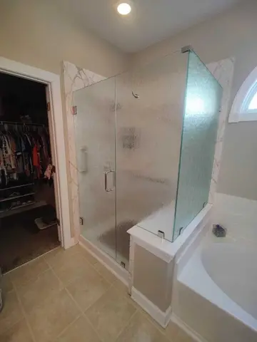 Frosted frameless glass panels around a shower with a swinging door and chrome hardware by Glass Doctor Home + Business of Myrtle Beach.