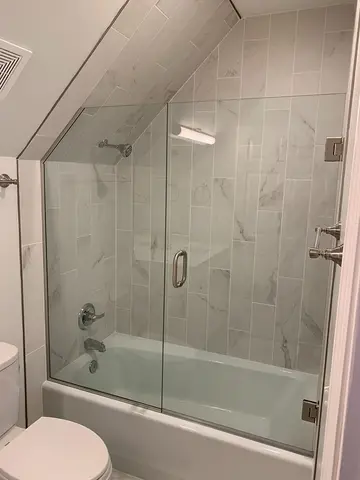 Frameless glass shower door panels with a swinging door installed by Glass Doctor of Nashville on a tub.