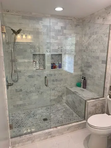A gray-tiled shower with a frameless glass enclosure and a swinging door installed by Glass Doctor of Nashville.
