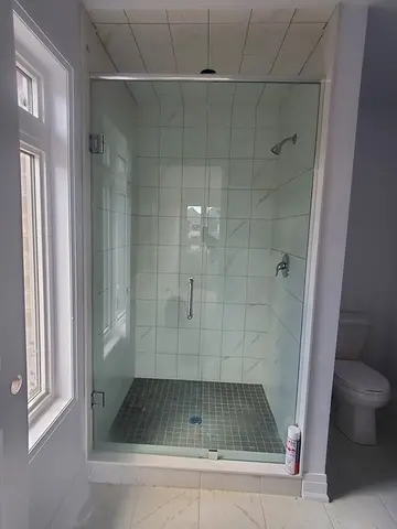 A walk-in shower with white tiles and a straight across glass shower door with a chrome header installed by Glass Doctor of Newmarket.