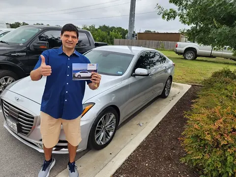 A satisfied customer of Glass Doctor Auto of Cedar Park gives a thumbs up in front of a silver car.