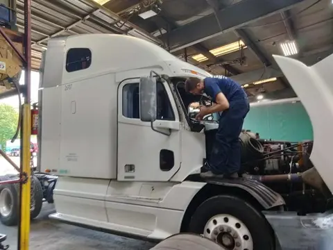 A Glass Doctor Auto of Southampton service professional working on a windshield replacement for a white semi truck in the shop.