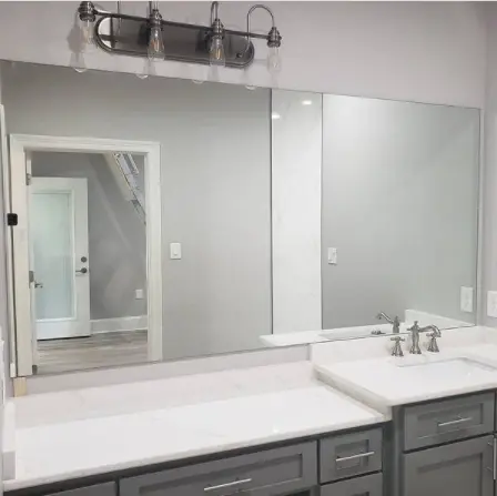 A frameless mirror installed over a sink and countertop by Glass Doctor of Tampa Bay.