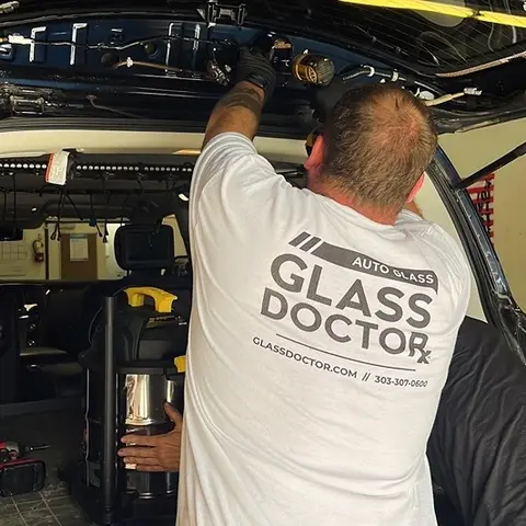 A Glass Doctor Auto of Castle Rock in a white shirt working on replacing the glass on the back hatch of an SUV.