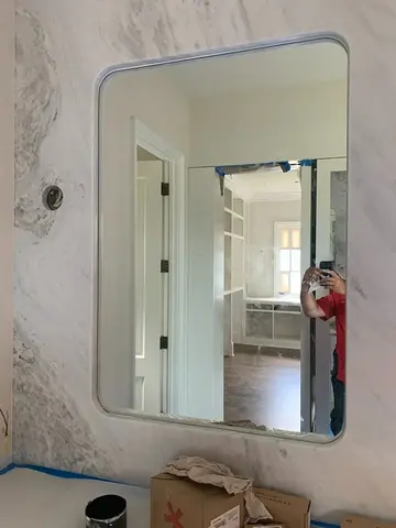 A mirror with rounded corners and recessed into a marble wall by Glass Doctor of Nashville.