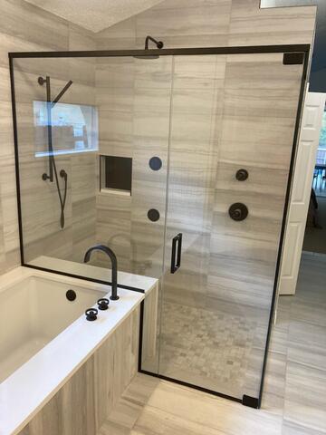 A tan and black shower featuring a semi-frameless glass enclosure installed by Glass Doctor of Pinellas County.