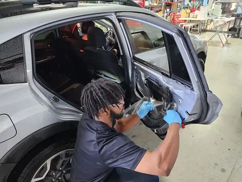 A service professional from Glass Doctor Auto of Cedar Park works to replace a rear door window on a car.