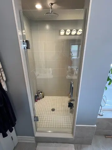 A walk-in shower with grey tiles and a single swinging frameless glass door installed by Glass Doctor of York Region.