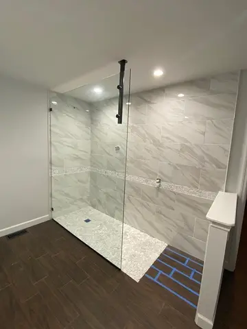 A frameless glass splash panel and ceiling mount on a gray tile shower by Glass Doctor of Raleigh