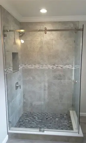 A custom frameless glass shower enclosure with a sliding glass door on a gray tiled shower by Glass Doctor of Tampa Bay.