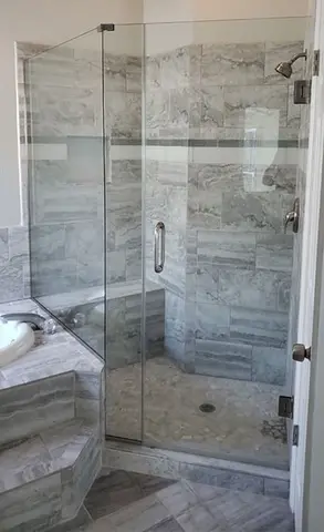 A frameless glass shower door installed at an angle on a tiled gray shower by Glass Doctor of Tampa Bay.