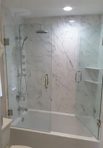 A frameless glass shower swinging door installed on a tub with white marbled tile by Glass Doctor of Tampa Bay.