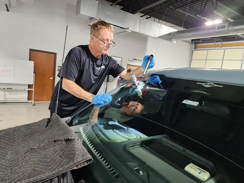 A Glass Doctor Auto of Cedar Park service professional works on repairing a rock chip in a windshield using a specialized tool.