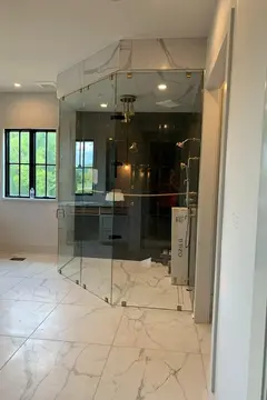 A large corner shower enclosure with two sides of frameless glass and an angled frameless glass door by Glass Doctor of Nashville.