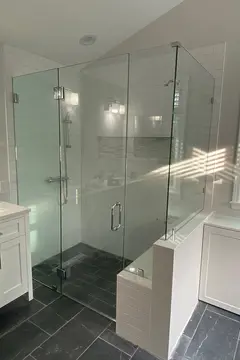 Frameless glass shower doors with a 90-degree angle and chrome hardware on a white tile shower by Glass Doctor of Raleigh