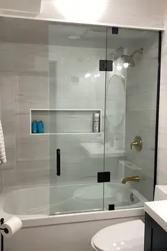A frameless glass shower door with black hardware on a bathtub by Glass Doctor of Barrie, ON.