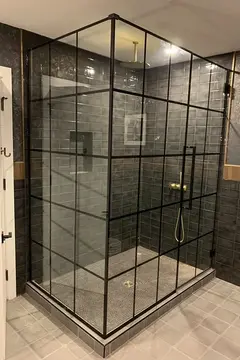 A corner shower with dark gray tiles and a black-framed glass enclosure on two sides from Glass Doctor of Nashville.