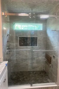 A tiled shower with frameless glass sliding doors and brushed nickel hardware by Glass Doctor of Raleigh