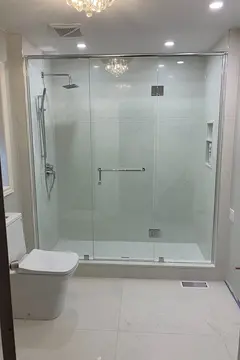 A semi-frameless shower enclosure with chrome top and side frames and hardware, and a center swinging glass door by Glass Doctor of Newmarket.
