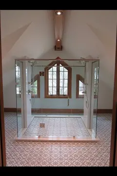 A custom 4-sided semi-frameless glass shower enclosure in front of a window by Glass Doctor of Barrie, ON.