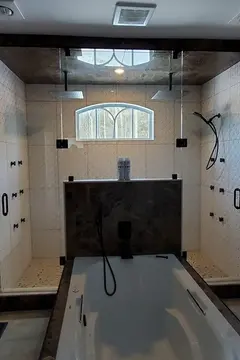 A white tiled shower room with a frameless glass enclosure and jack-and-jill doors on either side and black hardware by Glass Doctor of York Region.