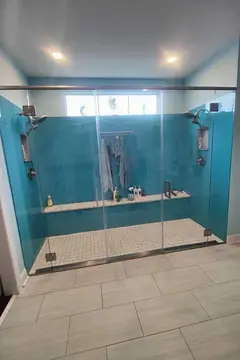 A double shower with blue walls and clear glass shower doors with a metal top frame and two swinging doors by Glass Doctor Home + Business of Myrtle Beach.