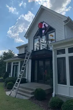 A Glass Doctor of Nashville service professional installing a feature window above the entry way of a house.