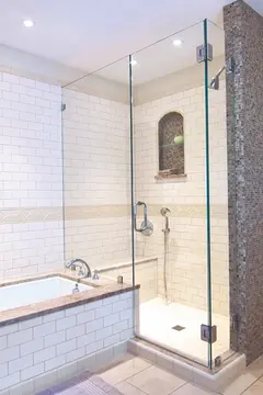 A decorative bathroom with a built-in tub next to a walk-in shower with a clear frameless glass shower enclosure with a swinging door.