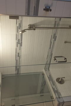A second angle of a tub with white and gray tiles and frameless glass shower doors installed by Glass Doctor of Sarasota.
