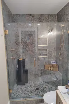 Gold hardware on frameless glass panels with a swinging door on a tile shower by Glass Doctor Home + Business of Myrtle Beach.