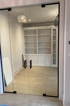 A semi-frameless glass wall with double swinging doors and black hardware installed on the entrance to an office by Glass Doctor of York Region.